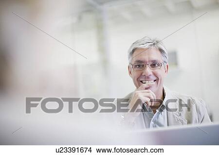 Picture - Businessman sitting at desk in office. Fotosearch