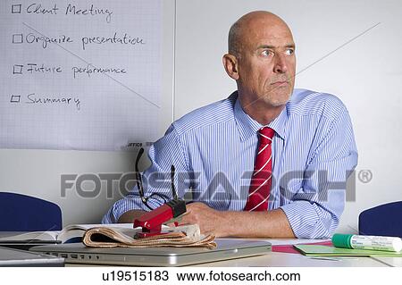 Stock Image - Businessman sitting at desk in office. Fotosearch