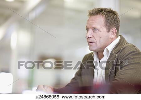 Businessman sitting at desk in office View Large Photo Image Stock Photography - Businessman sitting at desk in office. Fotosearch