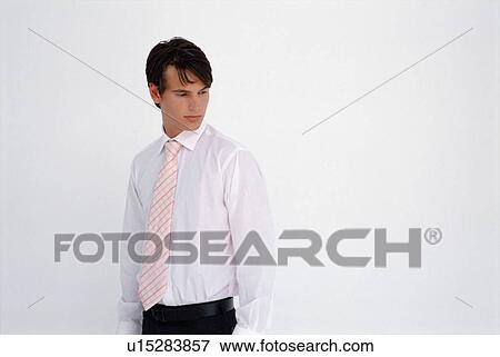 Stock Photo - Businessman standing against white wall. Fotosearch