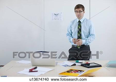 Businessman standing at conference desk View Large Photo Image Stock Image - Businessman standing at conference desk. Fotosearch