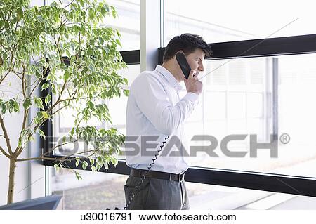 Businessman talking on phone in office View Large Photo Image Stock Image - Businessman talking on phone in office. Fotosearch