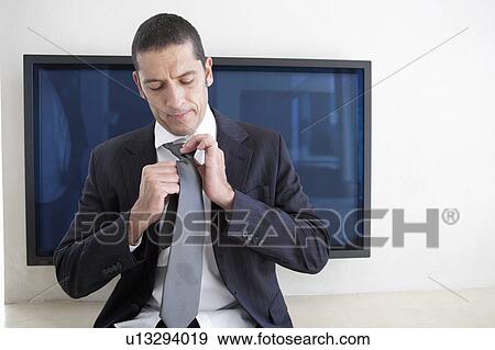 Businessman tying his tie in office View Large Photo Image Stock Photo - Businessman tying his tie in office. Fotosearch