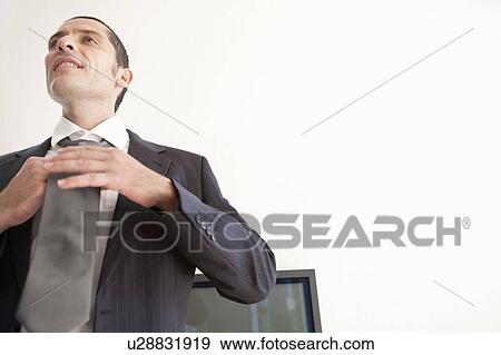 Businessman tying his tie in office View Large Photo Image Stock Photo - Businessman tying his tie in office. Fotosearch