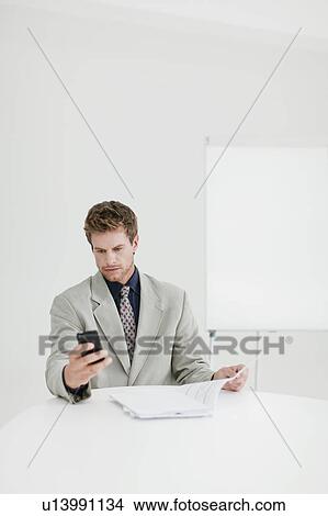 Picture - Businessman using cell phone in office. Fotosearch