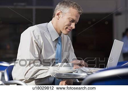 Businessman using laptop at cafe View Large Photo Image Stock Image - Businessman using laptop at cafe. Fotosearch