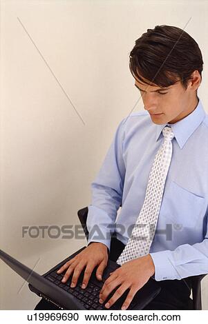 Businessman using laptop in office chair View Large Photo Image Stock Image - Businessman using laptop in office chair. Fotosearch