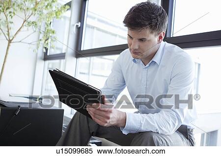Stock Photography - Businessman using tablet in office. Fotosearch
