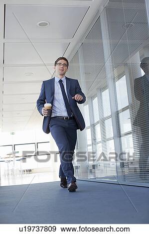 Businessman walking in empty office View Large Photo Image Stock Photo - Businessman walking in empty office. Fotosearch