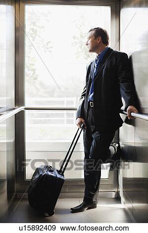 Stock Photo - Businessman with luggage in elevator. Fotosearch