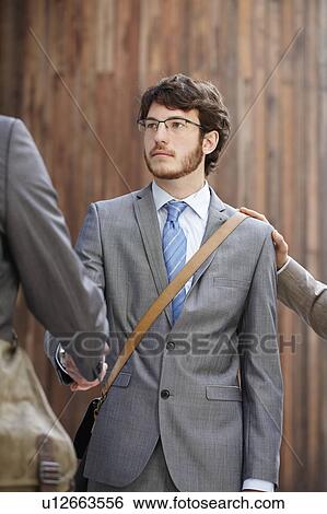 Stock Photograph - Businessmen shaking hands in courtyard. Fotosearch