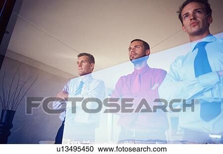 Stock Image - Businessmen standing at office window. Fotosearch
