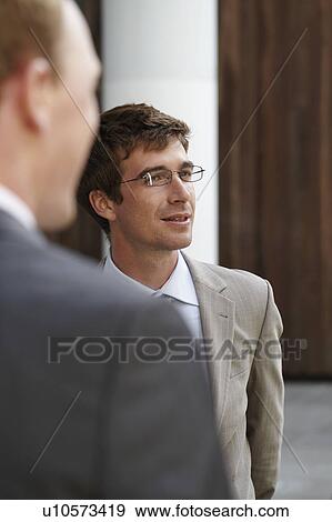 Stock Photo - Businessmen standing in courtyard. Fotosearch