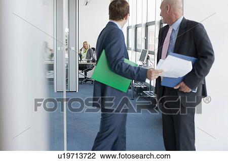 Stock Image - Businessmen talking in office. Fotosearch
