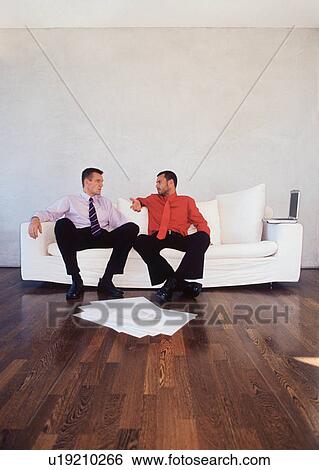 Stock Photograph - Businessmen talking on couch in office. Fotosearch