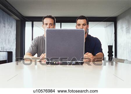 Picture - Businessmen using laptop together. Fotosearch