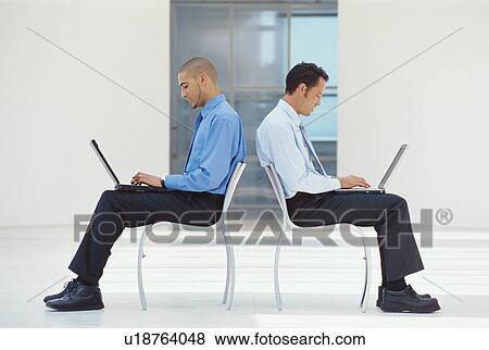 Businessmen using laptops in lobby View Large Photo Image Stock Photo - Businessmen using laptops in lobby. Fotosearch