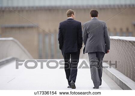 Businessmen walking on bridge together View Large Photo Image Picture - Businessmen walking on bridge together. Fotosearch