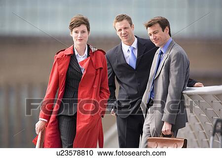 Stock Image - Businessmen watching female colleague. Fotosearch