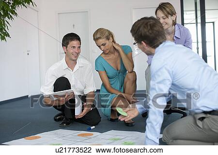 Businesspeople examining work in office View Large Photo Image Stock Image - Businesspeople examining work in office. Fotosearch