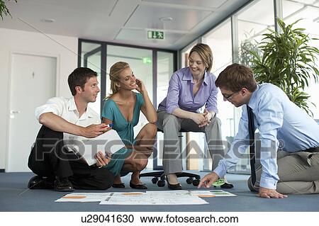 Businesspeople examining work in office View Large Photo Image Stock Image - Businesspeople examining work in office. Fotosearch