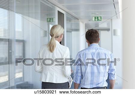 Stock Image - Businesspeople walking in office. Fotosearch