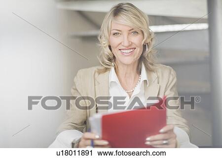 Stock Image - Businesswoman holding folders in office. Fotosearch