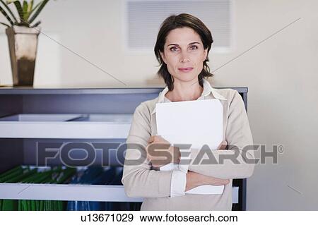 Businesswoman holding papers in office View Large Photo Image Stock Photo - Businesswoman holding papers in office. Fotosearch