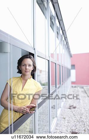 Picture - Businesswoman leaning out office window. Fotosearch
