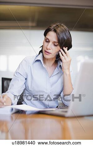 Stock Image - Businesswoman on cell phone and laptop. Fotosearch