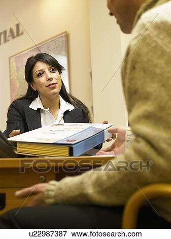 Stock Photo - Businesswoman passing folder to client. Fotosearch
