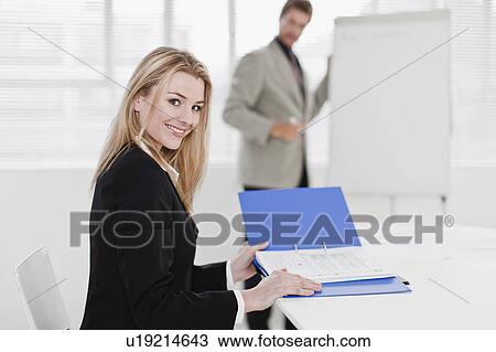 Businesswoman reading binder in office View Large Photo Image Stock Image - Businesswoman reading binder in office. Fotosearch