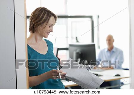 Businesswoman reading papers in office View Large Photo Image Stock Photography - Businesswoman reading papers in office. Fotosearch