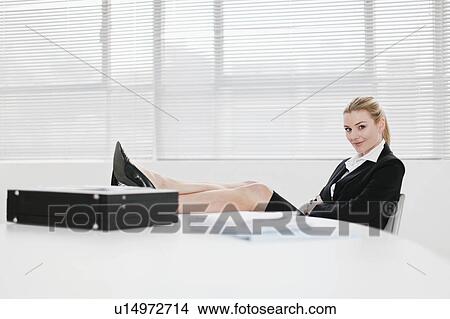 Picture - Businesswoman relaxing with feet on desk. Fotosearch