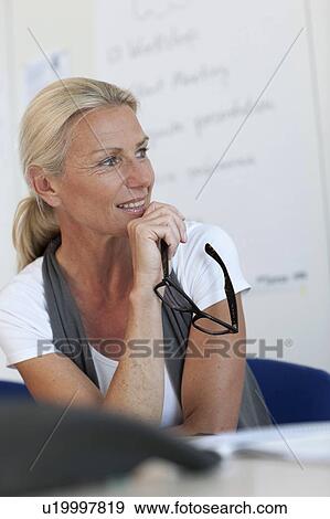 Stock Photo - Businesswoman sitting at desk in office. Fotosearch
