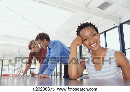 Stock Photography - Businesswoman smiling at desk. Fotosearch