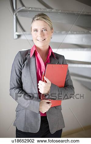 Stock Image - Businesswoman smiling in office. Fotosearch