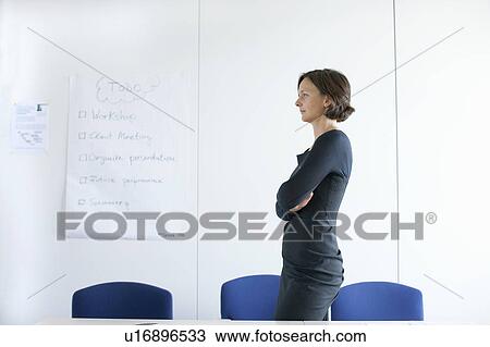Stock Image - Businesswoman standing in empty office. Fotosearch