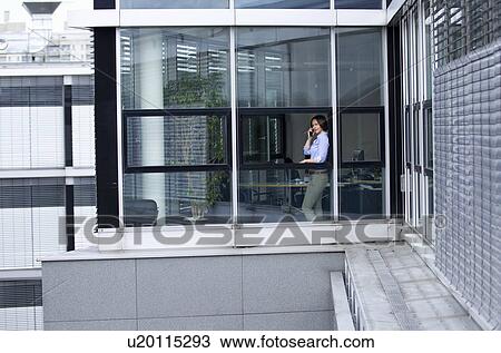 Businesswoman talking on phone in office View Large Photo Image Stock Image - Businesswoman talking on phone in office. Fotosearch
