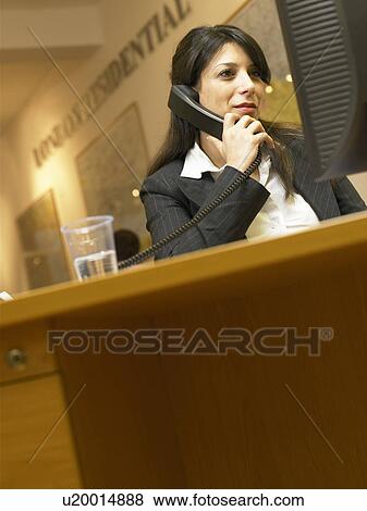 Stock Photo - Businesswoman talking on phone in office. Fotosearch