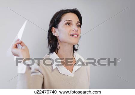 Stock Image - Businesswoman throwing paper airplane. Fotosearch