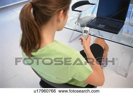 Businesswoman using cell phone in office View Large Photo Image Stock Photograph - Businesswoman using cell phone in office. Fotosearch