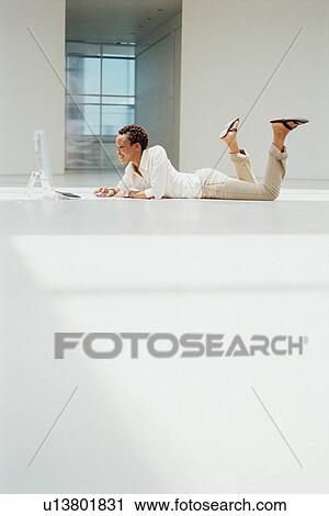 Stock Image - Businesswoman using computer on floor. Fotosearch