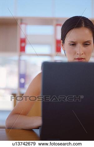 Stock Photo - Businesswoman using laptop in office. Fotosearch