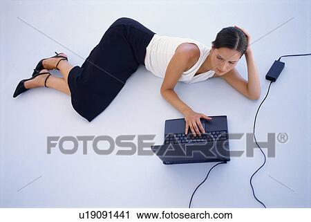 Stock Image - Businesswoman using laptop on floor. Fotosearch