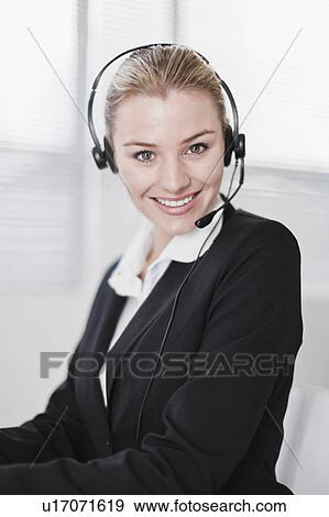 Stock Photo - Businesswoman wearing headset in office. Fotosearch