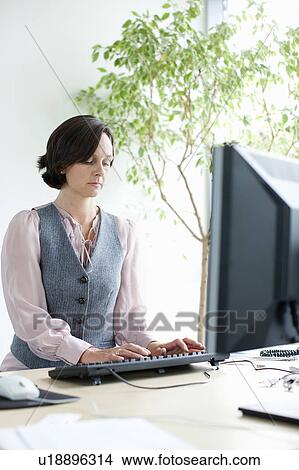 Picture - Businesswoman working at desk. Fotosearch