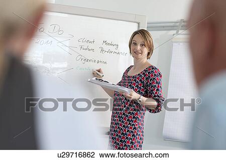 Stock Image - Businesswoman writing on whiteboard. Fotosearch