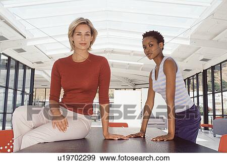 Businesswomen smiling at desk View Large Photo Image Stock Photo - Businesswomen smiling at desk. Fotosearch
