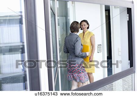 Stock Image - Businesswomen talking in office. Fotosearch